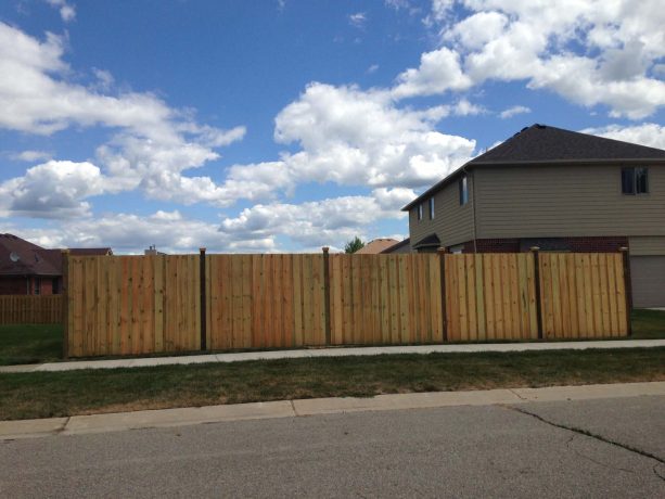 a light-color wood board on board style fencing with darker posts