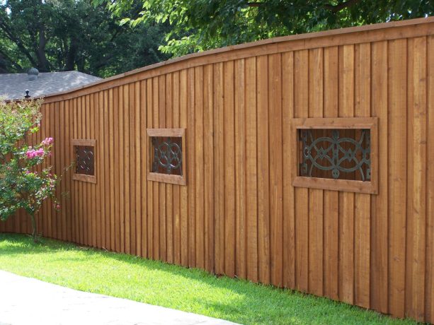 the board on board fencing looks more decorative because of the wrought iron windows