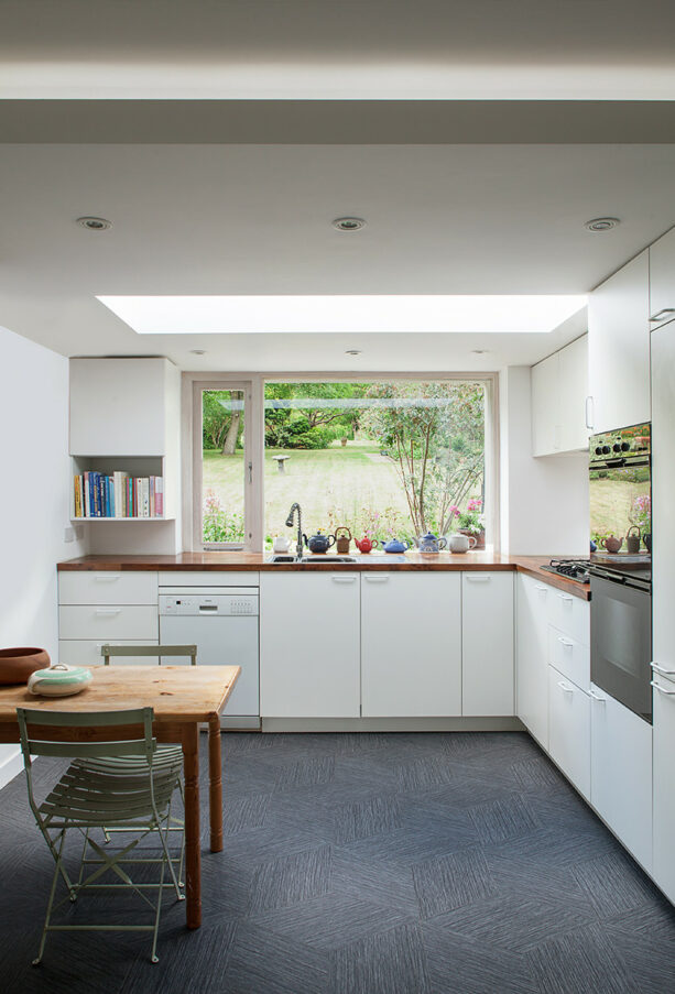 a collection of beautiful teapots placed in a large, panoramic kitchen garden window right over a sink with drainboard