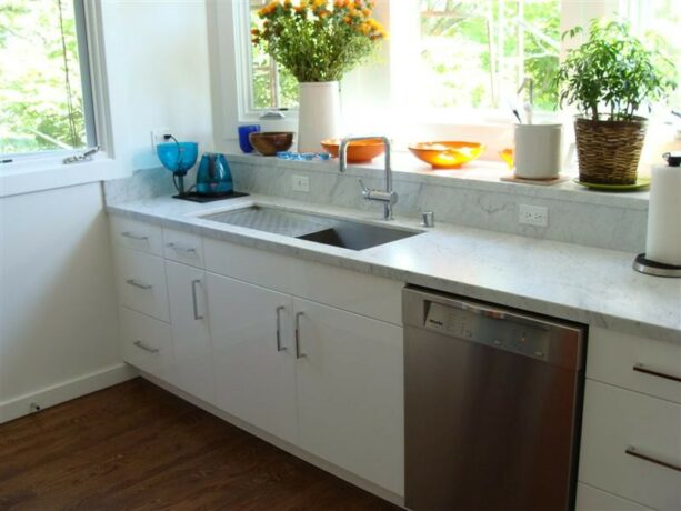 an enormous garden window with deeper sill for more storage over an undermount stainless steel kitchen sink