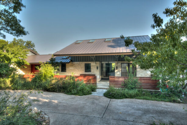 a contemporary exterior pairing a burnished slate metal roofing with warm white natural stone wall